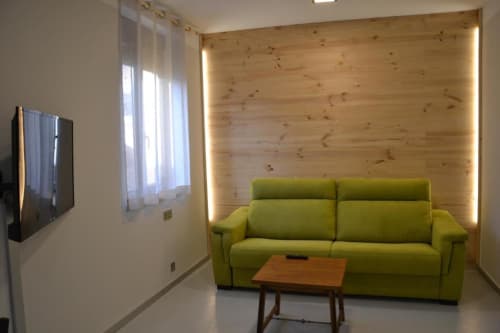 Moderno salón de apartamento con sofá verde, pared de madera y vista a la ciudad en el hotel RJ26 León