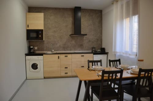 Cocina y comedor modernos en Apartamentos RJ26 León con muebles de madera, electrodomésticos negros y zona de comedor
