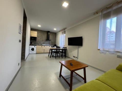 Sala de estar moderna con zona de comedor, cocina, televisor y vistas a la ciudad en RJ26 León
