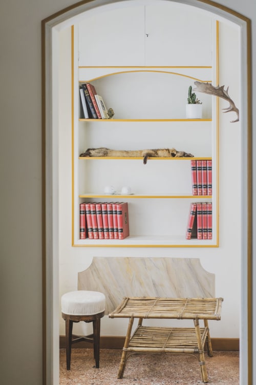 Built-in shelving with gold trim displays books, plants, and hunting decor in Camera della Caccia at Villa Stecchini Resort