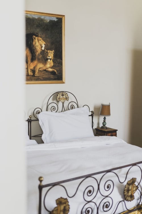 Elegant bedroom at Villa Stecchini Resort with ornate iron bed, white linens, and lion portrait above headboard
