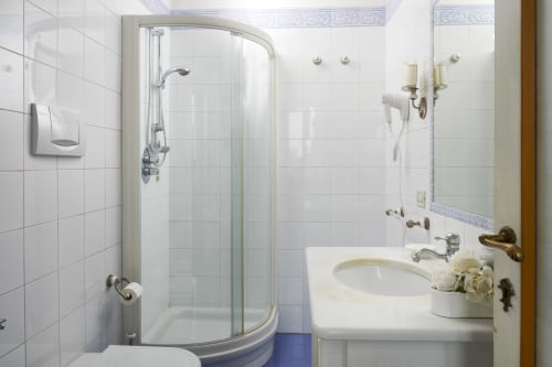 Clean white-tiled bathroom with curved shower enclosure, sink, and toiletries at Villa Stecchini Resort in Romano d'Ezzelino
