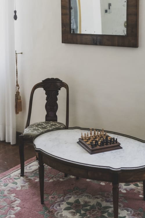 Elegant room at Villa Stecchini Resort with marble table, chess set, ornate dark chair, and framed mirror in Romano