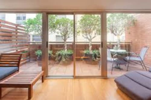 Modern Valencia loft with wooden floors, glass doors opening to terrace with city views and outdoor seating
