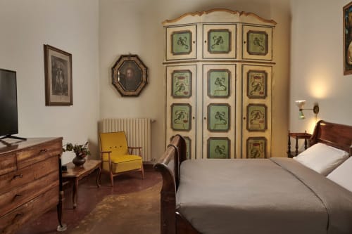 Elegant bedroom at Villa Stecchini Resort with vintage wardrobe, wooden furniture, yellow chair, and terracotta floor in