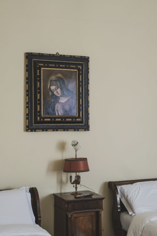 Ritratto rinascimentale incorniciato sopra comodino in legno con lampada nella suite Villa Stecchini Resort, Romano d'Ezzelino