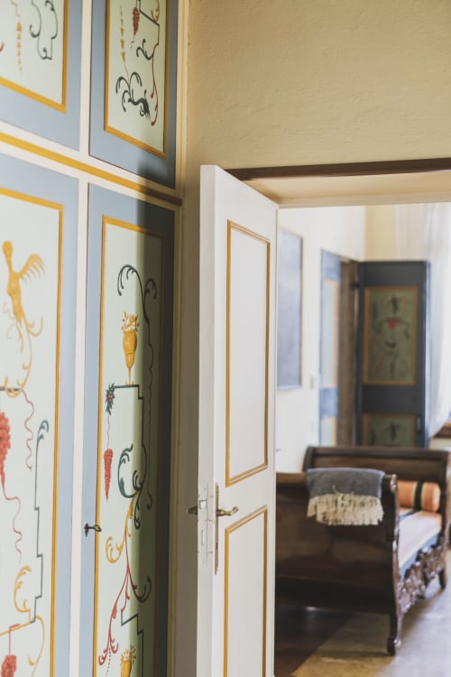 Elegante corridoio con opere botaniche dipinte a mano e porte con cornice dorata nella suite di Villa Stecchini Resort a Romano