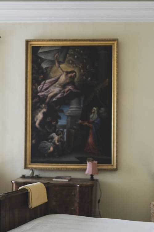 Quadro classico incorniciato sopra la scrivania in legno nella Suite Villa Stecchini con lampada rosa e asciugamano bianco