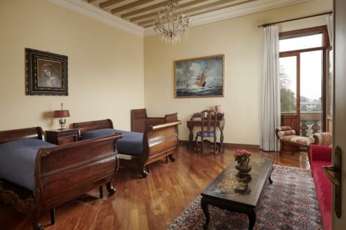 Elegante camera da letto della suite a Villa Stecchini Resort con letti gemelli, mobili in legno, lampadario e vista sul lago a Romano