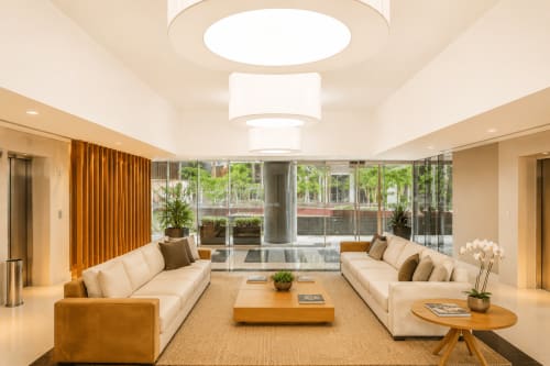 Lounge moderno com sofás creme, acabamentos em madeira e janelas panorâmicas com vista para o horizonte de Brasília em luxuosa pousada