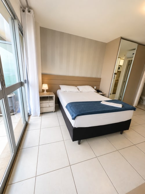 Quarto moderno na ALUGUEASY em Brasília com cama queen, varanda com vista para a cidade e design acessível para cadeirante