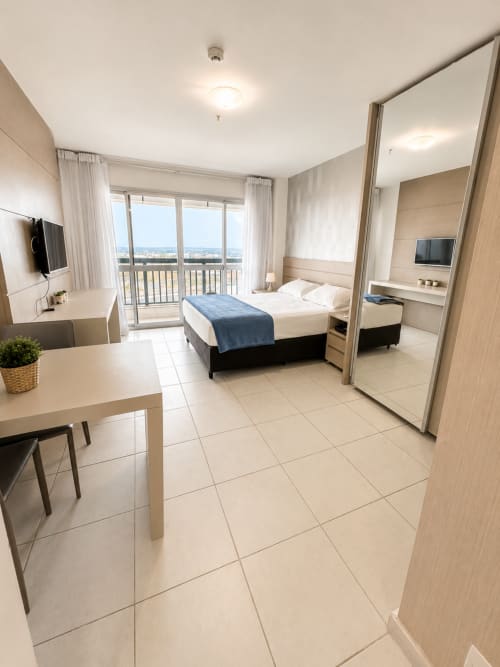 Quarto moderno em hotel de Brasília com vista para a cidade, varanda, cama king, escrivaninha, TV de tela plana e design acessível para cadeirantes