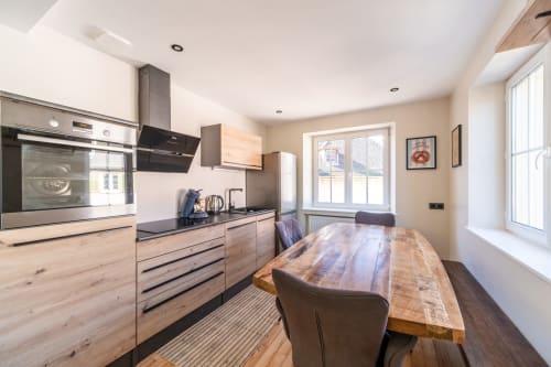 Cocina moderna y comedor en el apartamento Les Ambrades, Kaysersberg con mesa de madera y electrodomésticos de acero inoxidable