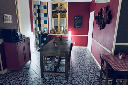 Salle à manger Au Richebourg Nogent avec murs bordeaux, carrelage à motifs, table noire et vitrines en verre coloré