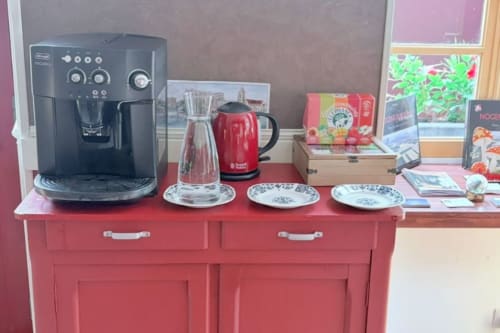Armoire de cuisine rouge avec machine à espresso, bouilloire rouge et assiettes décoratives à l'Au Richebourg Nogent