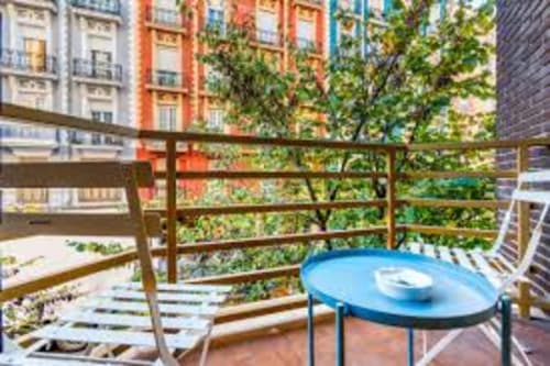 Spacious Valencia apartment balcony with blue table, wooden railing, city views, and surrounding colorful buildings in