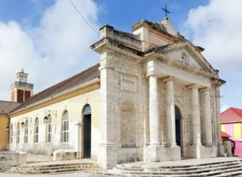Église historique en pierre blanche avec colonnes à Le Moule, Guadeloupe, architecture classique et détails de toit rouge