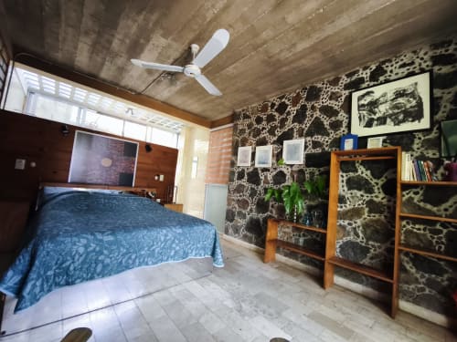 Habitación estándar en Casa Santi Tepoz con cama azul, muebles de madera, paredes decoradas, ventilador de techo y televisión