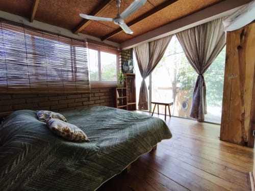 Suite Junior espaciosa en Casa Santi Tepoz con vistas al jardín, vigas de madera, ventilador de techo y acceso a terraza