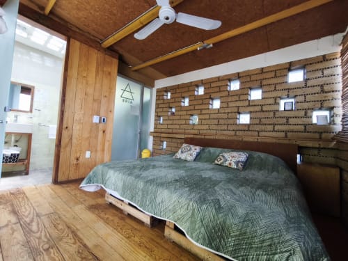 Dormitorio rústico en Casa Santi Tepoz, Santiago Tepetlapa, con vigas de madera, cama matrimonial, pared de ladrillo con repisas y techo
