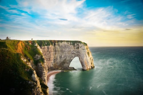 Dramatic white chalk cliffs with natural stone arch overlooking turquoise sea in Normandy, France