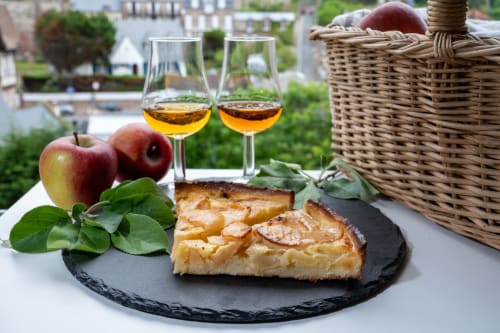 Apple tart with wine glasses overlooking Normandy rooftops at Skol In Normandy hotel