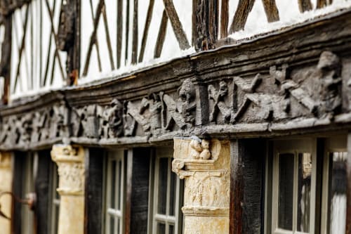 Historic timber-framed architecture with ornate stone carvings at Skol In Normandy hotel