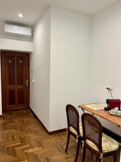 Camera moderna presso Domus Giovanna Roma con scrivania in legno, sedie, parquet, climatizzatore e porta in legno scuro