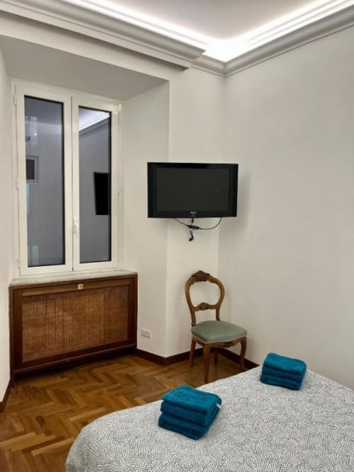 Camera moderna a Domus Giovanna Roma B&B con TV a schermo piatto, cassettone in legno e asciugamani blu