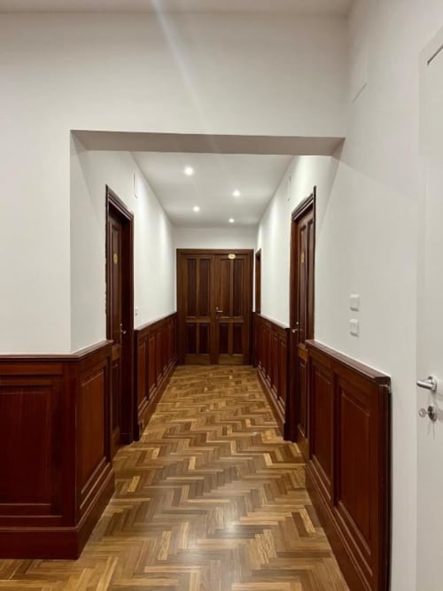 Corridoio moderno della Domus Giovanna B&B Roma con porte in legno, pavimento a spina di pesce e pareti bianche