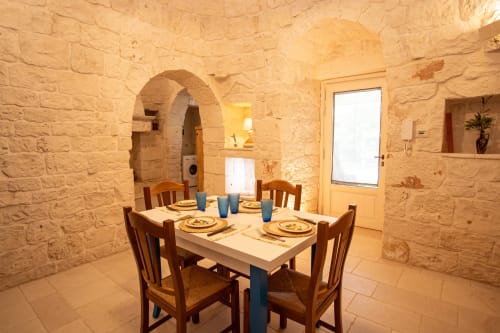 Sala da pranzo in una casa Trulli in pietra ad Trulli Life, Ostuni con tavolo apparecchiato e arcata
