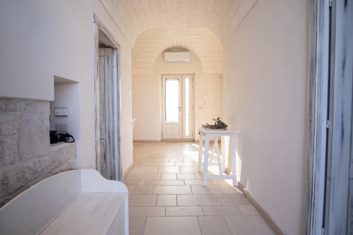 Corridoio luminoso nella casa Trulli Life di Ostuni, con soffitto a volta, pavimenti piastrellati e comfort moderni