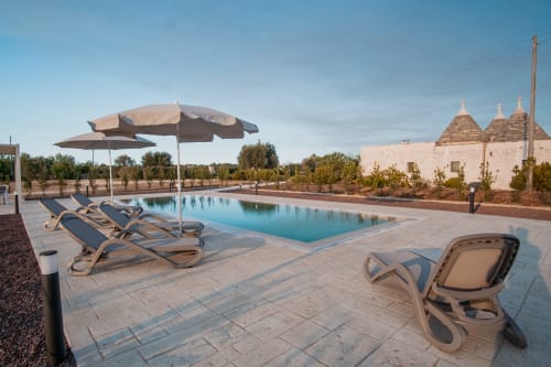 Piscina del resort Trulli Life con lettini e ombrellone, Ostuni Italia con i tradizionali edifici trulli