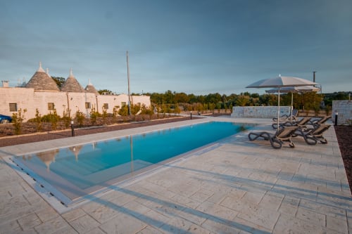 Resort Trulli Life a Ostuni con tradizionali costruzioni in trullo, piscina e lettini con vista sulla campagna pugliese