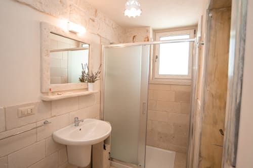 Bagno moderno con doccia al cottage Trulli Life di Ostuni, con pareti in piastrelle, lavandino e specchio