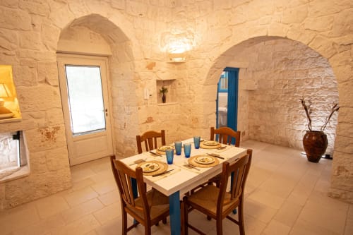 Sala da pranzo in una trulli a Ostuni con volte in pietra, tavolo apparecchiato e sedie in legno tradizionali
