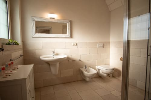 Bagno spazioso a Trulli Life Ostuni con lavabo su piedistallo, bidet, wc, doccia e specchio - cottage Trullamie Terra Rossa