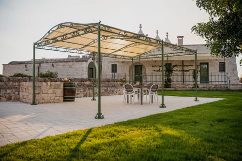 Patio all'aperto con pergolato in metallo presso il resort Trulli Life a Ostuni, con posti a sedere e architettura in pietra