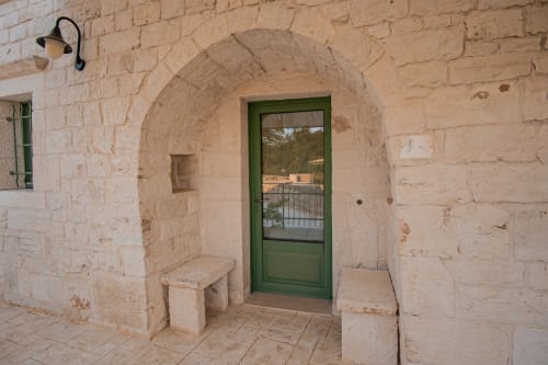 Ingresso in pietra ad arco con porta verde presso il resort Trulli Life a Ostuni, Italia