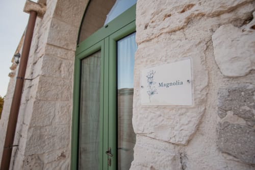 Ingresso con porta verde della casa Magnolia al resort Trulli Life di Ostuni, Italia, con muri in pietra tradizionali