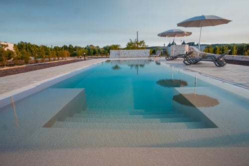 Lussuosa piscina del resort Trulli Life a Ostuni con lettini, ombrelloni e vista sulla campagna pugliese
