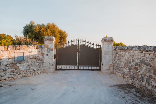 Cancello d'ingresso del resort Trulli Life con muri in pietra e alberi autunnali a Ostuni, Italia