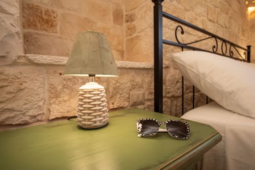 Comodino con lampada intrecciata e occhiali da sole nella camera Salvia di Trulli Life, Bari, Italia