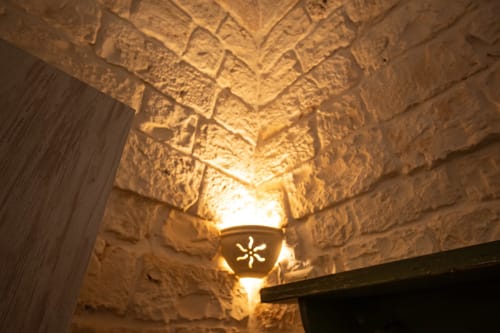Soffitto e pareti in pietra illuminati nella camera Salvia di Trulli Life, Bari, che mostrano l'architettura tradizionale pugliese