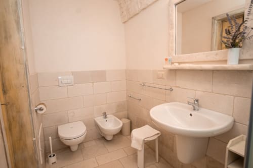 Bagno della camera Salvia dell'hotel Trulli Life a Bari con WC, bidet, lavabo e pareti piastrellate