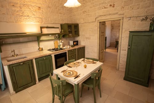 Cucina verde con tavolo da pranzo presso l'hotel Trulli Life a Bari, Italia
