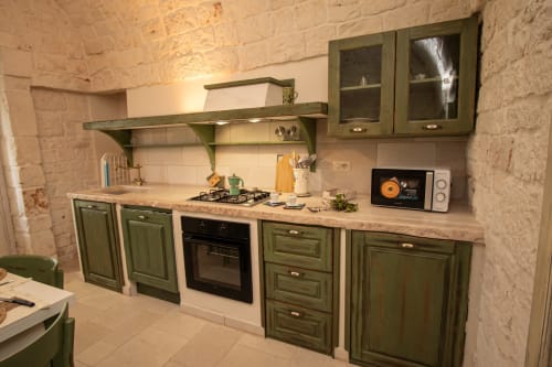 Cucina verde con muri in pietra nella camera Salvia di Trulli Life, Bari, con fornello a gas e microonde