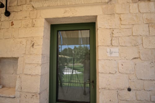 Porta verde con pannello in vetro all'hotel Trulli Life di Bari, Italia, con vista giardino dalla finestra