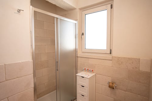 Bagno moderno nell'hotel Trulli Life di Ostuni, con box doccia piastrellato e finestra