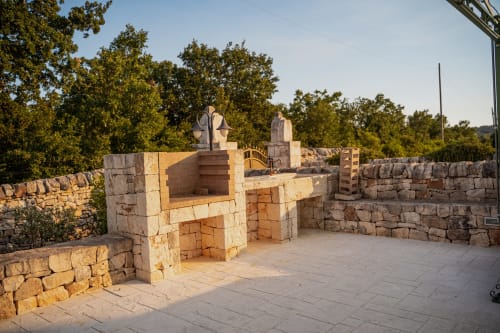 Terrazza in pietra con forno tradizionale all'hotel Trulli Life di Ostuni, circondata da muri antichi e vegetazione lussureggiante